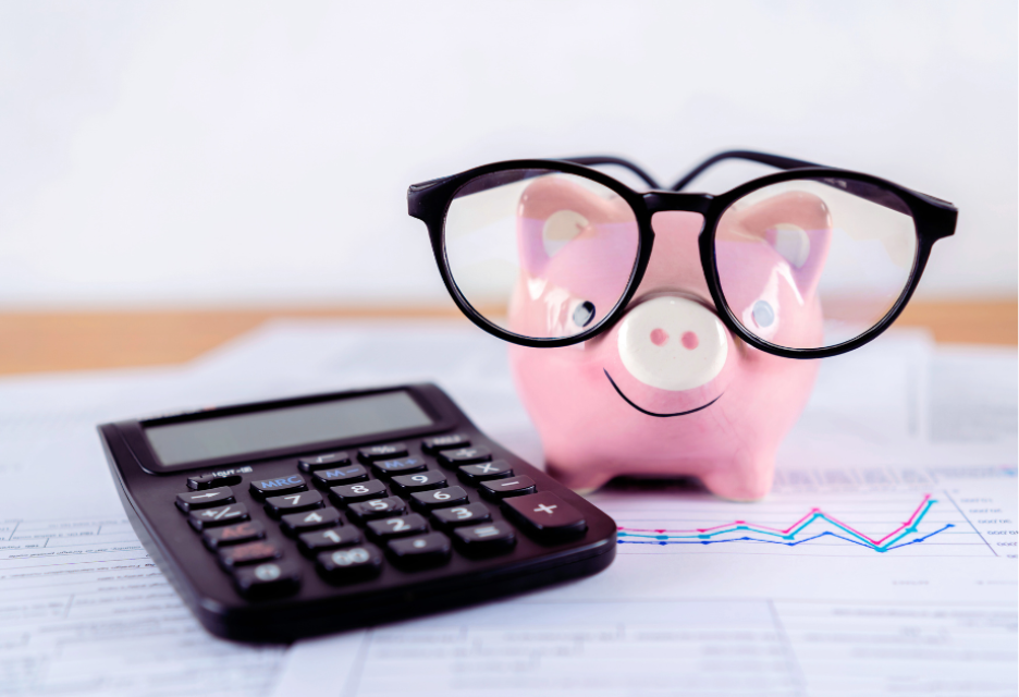 Piggy bank wearing glasses beside a calculator and financial charts, representing budgeting, savings, and commercial property investment planning.